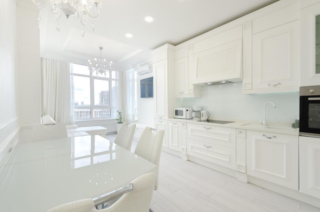 eine weiße Küche mit weißen Schränken sowie einem Tisch und Stühlen in der Unterkunft 10353 Residential complex Central Park cozy apartment in Kiew
