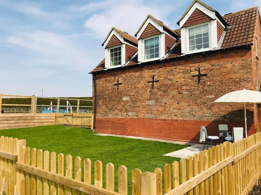 a brick house with an umbrella and a yard at Grove Farm Loft Annexe Includes Continental Breakfast in Lincoln