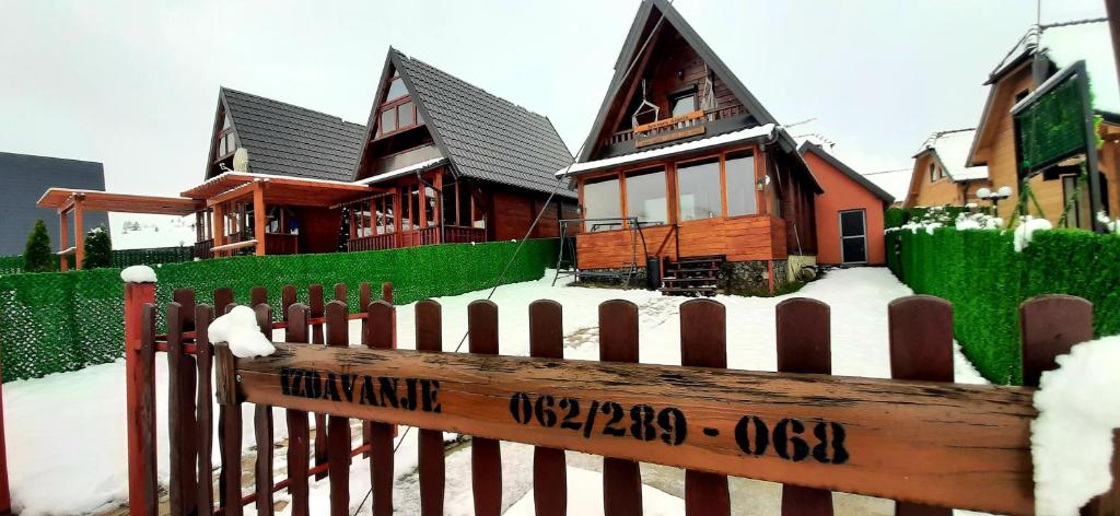 a wooden fence in front of a house with snow at Brvnara Čigota in Zlatibor