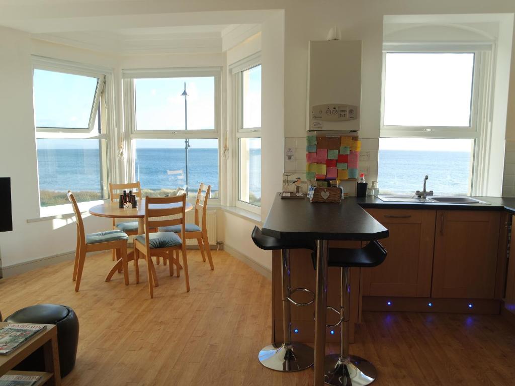 a kitchen and dining room with a view of the ocean at Gwel Y Mor in Pwllheli