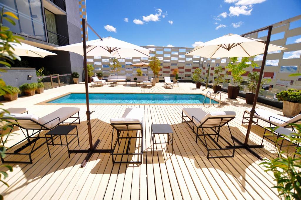 a patio with tables and umbrellas and a pool at Hotel Casino Talca in Talca