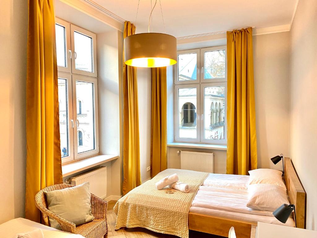 a bedroom with yellow curtains and a bed and a chair at Faust Apartments in the Heart of Kazimierz in Krakow