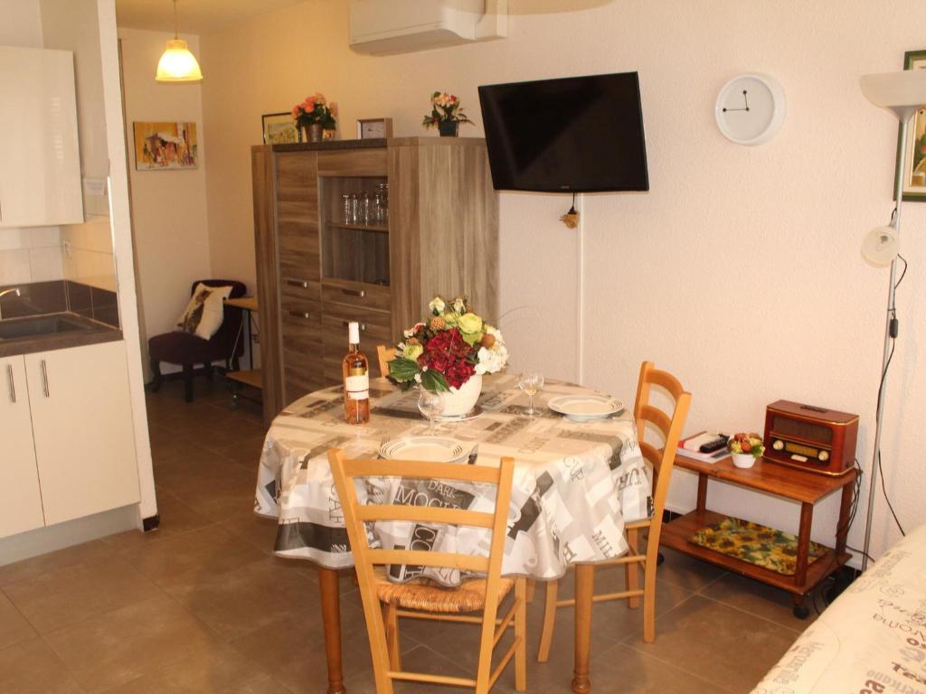 une salle à manger avec une table, des chaises et une télévision dans l'établissement Appartement avec Jardinet Privatif à Balaruc-les-Bains, près des Thermes - Classé ⭐⭐ - FR-1-503-51, à Balaruc-les-Bains