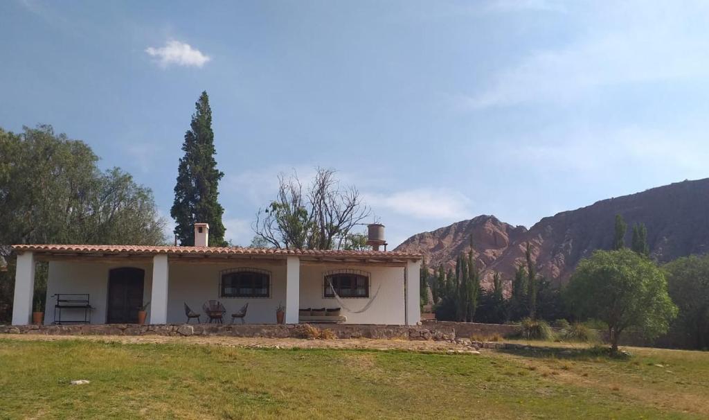 a small white house with mountains in the background at Casona Inkill Huasi II in Tilcara