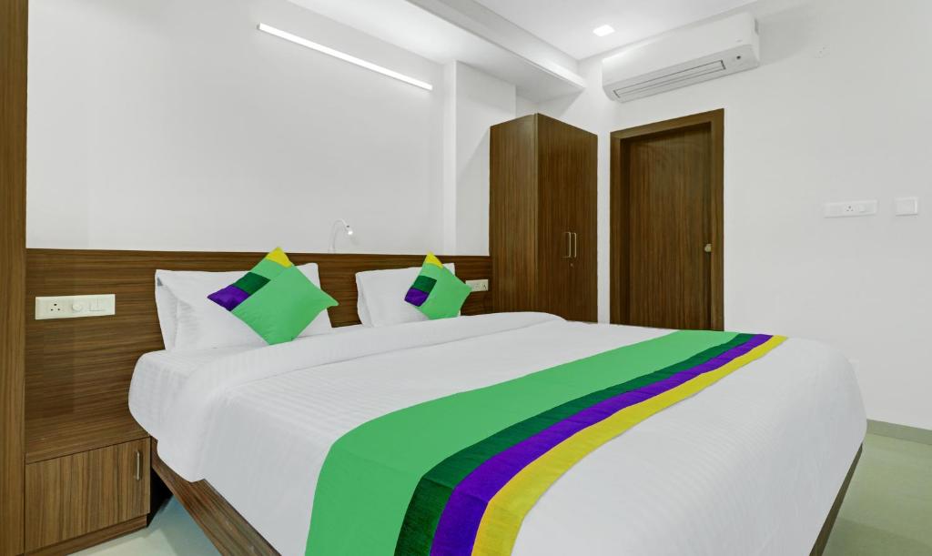 a bedroom with a white bed with a rainbow blanket at Treebo Trend Raga in Visakhapatnam
