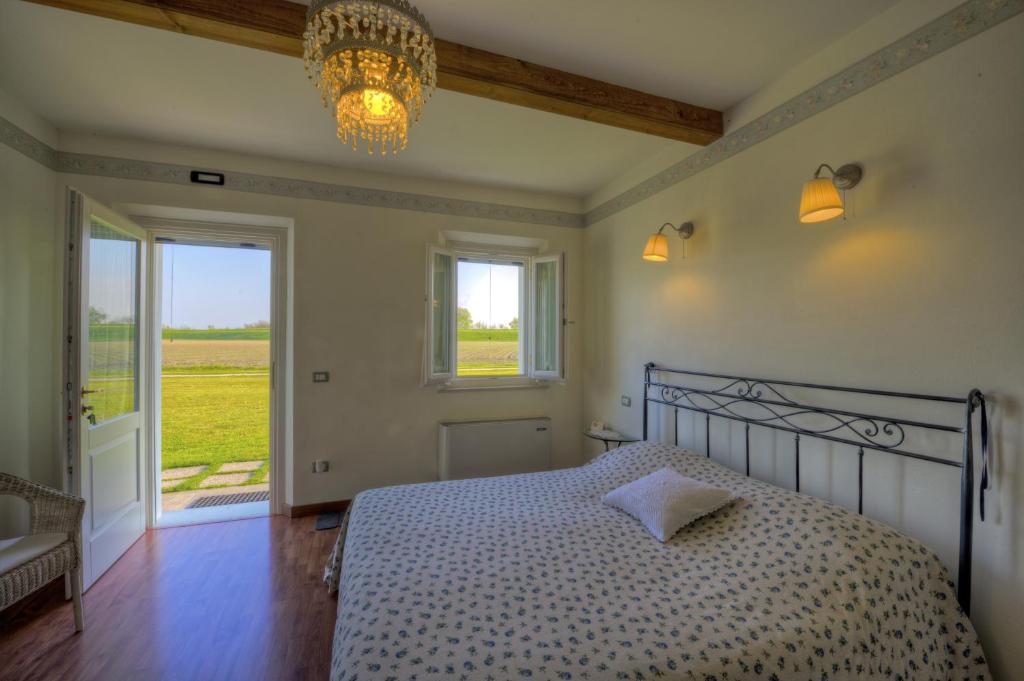 a bedroom with a bed and a window and a chandelier at B&B Corte Bertoia in San Benedetto Po