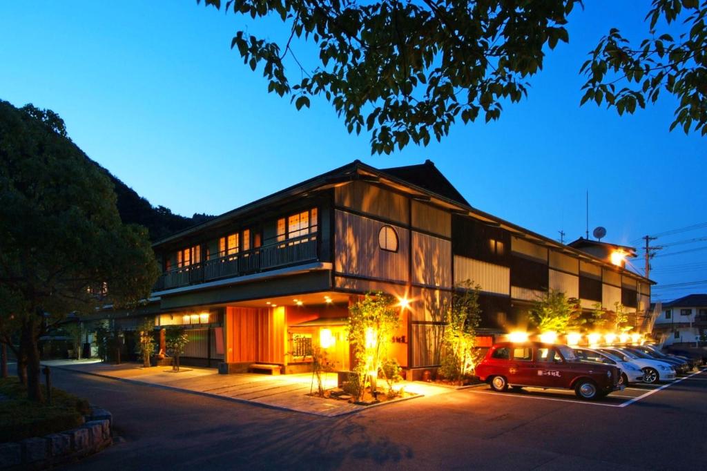 un edificio con coches estacionados en un estacionamiento por la noche en Onishiya Suishoen, en Toyooka