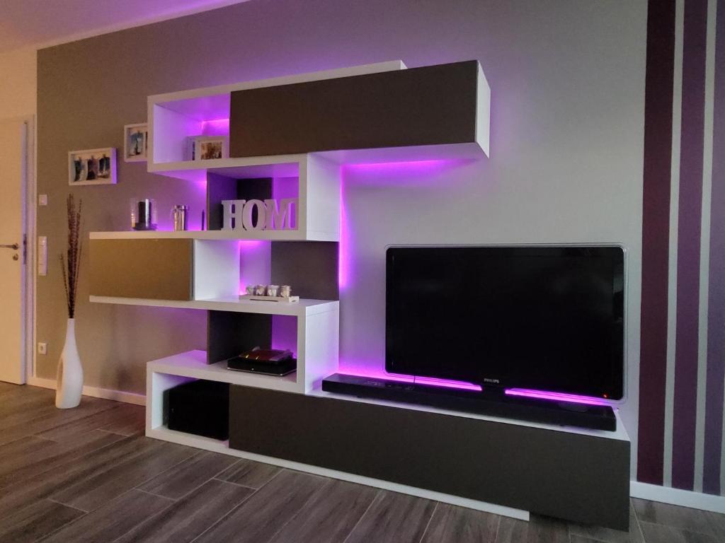 ein Wohnzimmer mit einem TV mit violetten Lichtern in der Unterkunft Leipziger Neuseenland Apartment in Markkleeberg