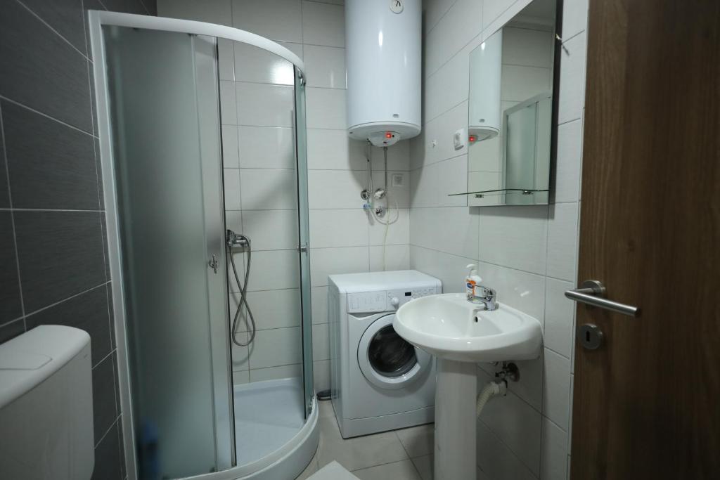 a bathroom with a shower sink and a washing machine at Apartman Lux in Nova Pazova