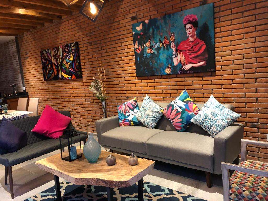 a living room with a couch and a brick wall at Doña Jose Suite & Apartments in San Miguel de Allende