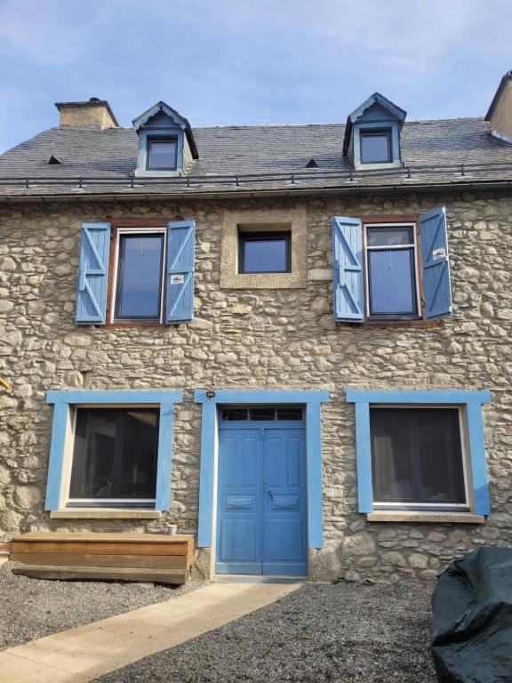 uma casa de pedra com portas e janelas azuis em Les 4 étoiles de MAÉÉ em Cazeaux-de-Larboust