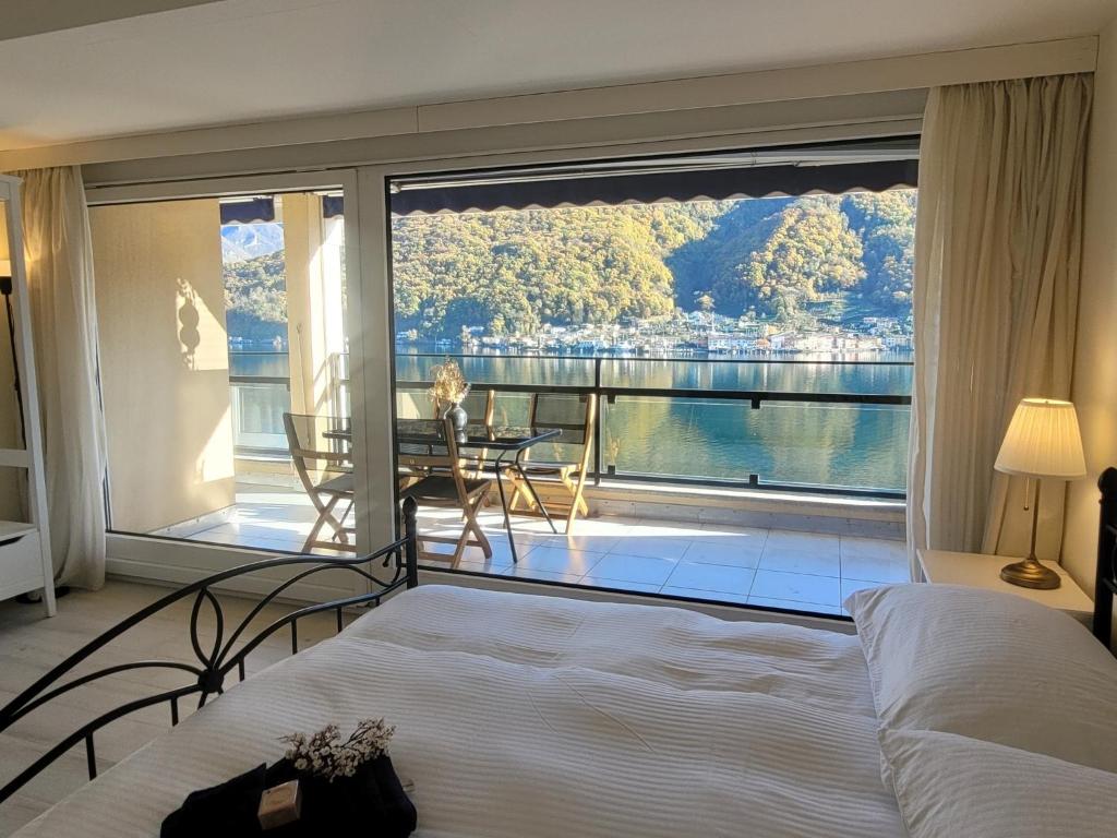 een slaapkamer met een groot raam met uitzicht op het water bij La Farfalla in Brusino Arsizio