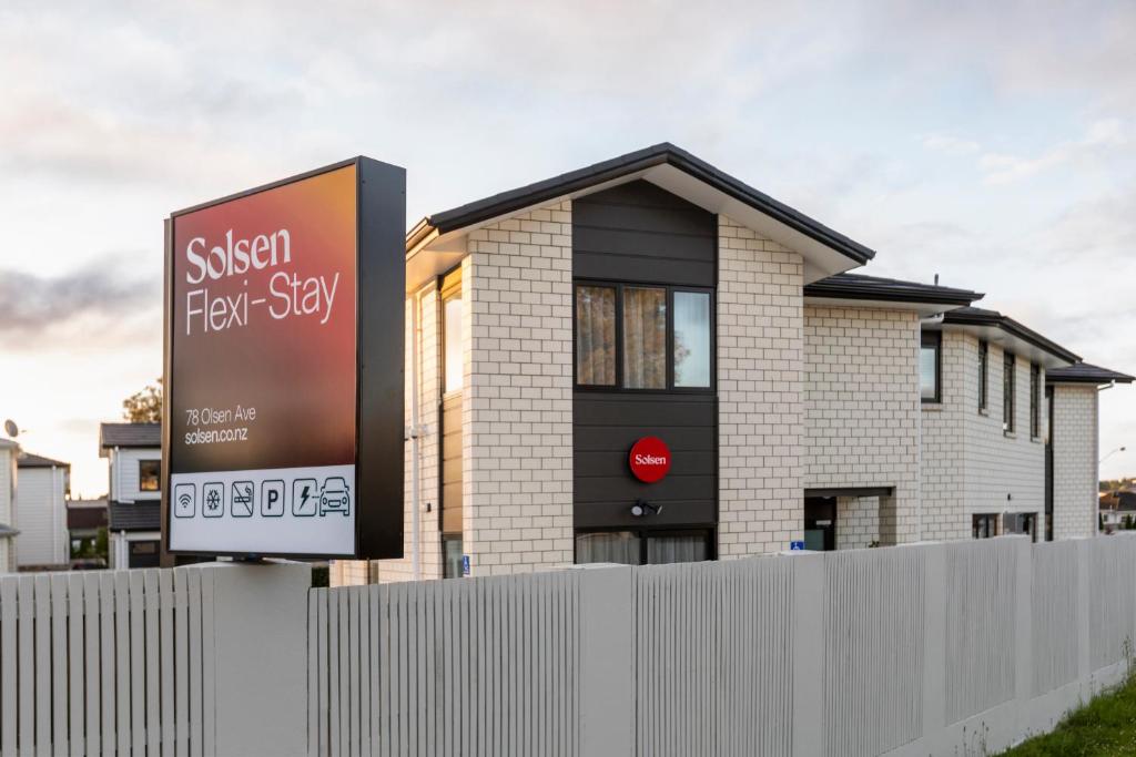 a sign in front of a house behind a fence at Solsen Flexi-Stay in Auckland