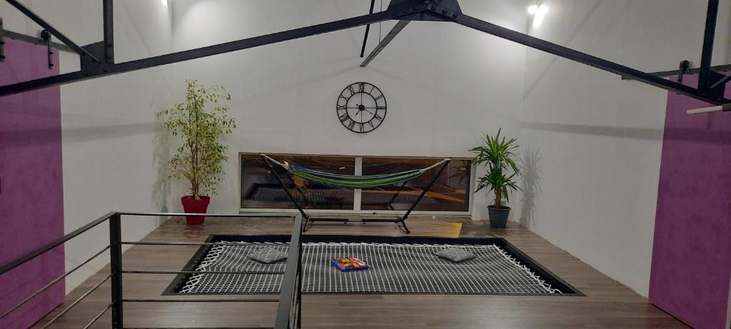 a room with a hammock and a clock on a wall at Loft atypique et chaleureux in Châteauroux