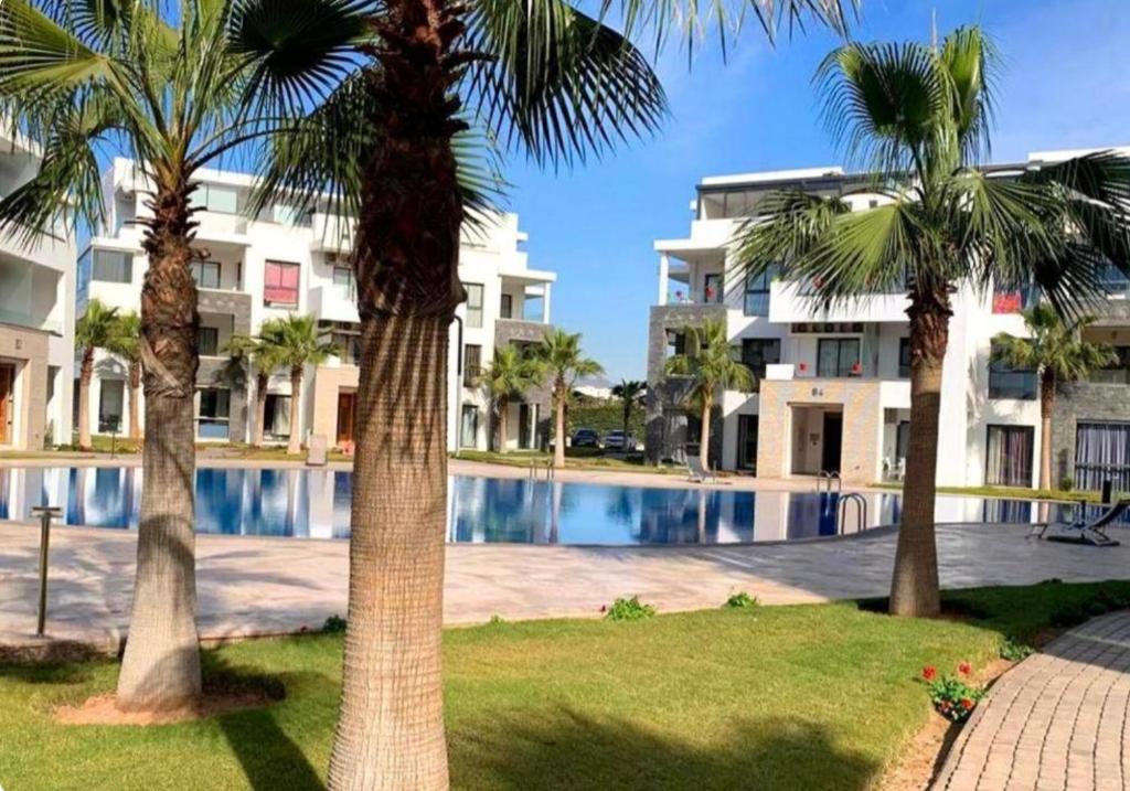 a group of palm trees in front of a building at Luxury spacious 3 Bed apt with pool in Agadir