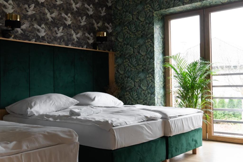 two beds in a bedroom with a green wall at Nad Strumykiem in Jabłonna Majątek