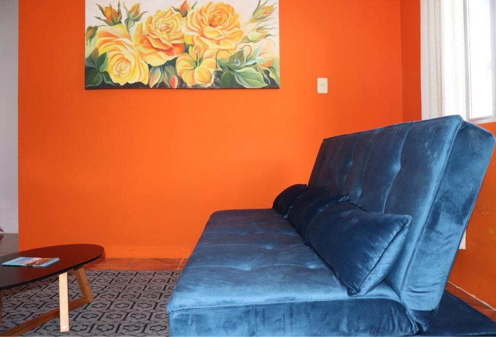 um sofá azul numa sala de estar com uma parede laranja em Casa de praia da Kenna, centro em Navegantes