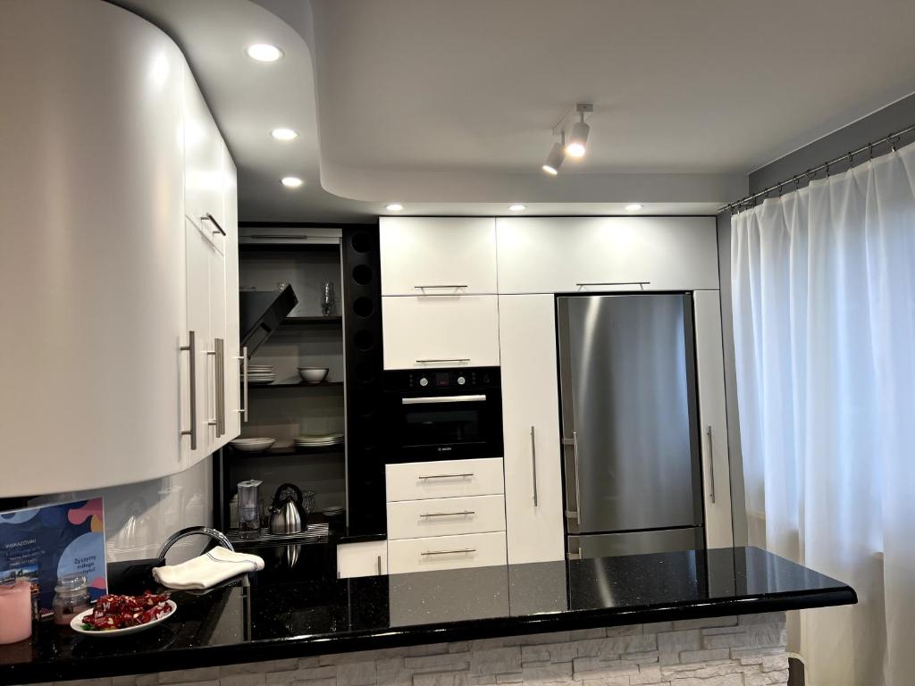 a kitchen with white cabinets and a black counter top at Apartament Tuwima 6 in Ełk