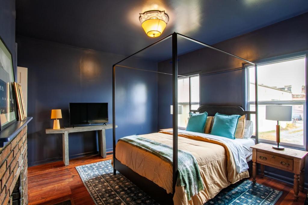 Pruett Place Downtown Home في نوكسفيل: غرفة نوم مع سرير المظلة والجدران الزرقاء