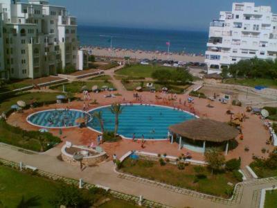 une grande piscine dans un parc à côté de l'océan dans l'établissement Cité Jardins Appartement, à Martil
