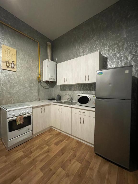 リヴィウにあるROMANTIC Apartments - city center 5 15のキッチン(白いキャビネット、ステンレス製の冷蔵庫付)