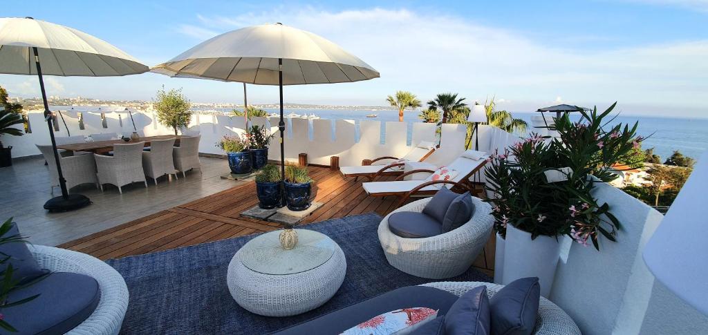 a balcony with chairs and tables and an umbrella at Best seaview Penthouse+77m2 privat roof terrace near beach and Cannes in Vallauris