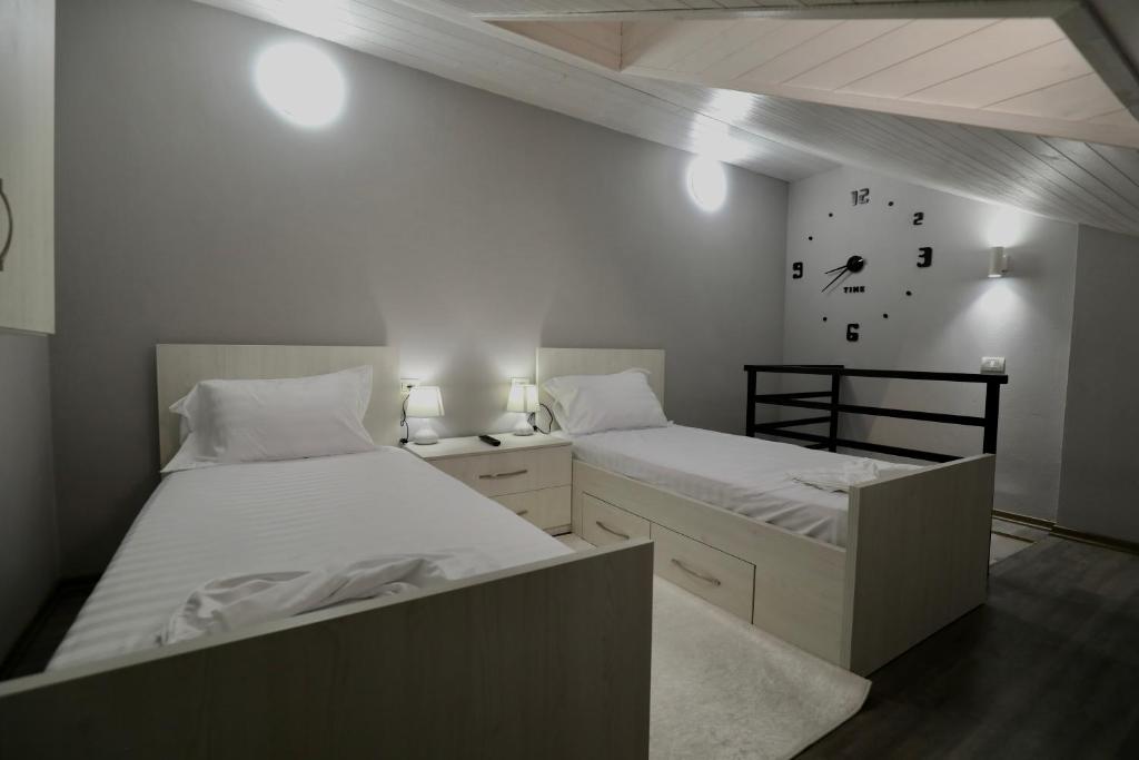 um quarto com duas camas e um relógio na parede em Old Town Inn em Pogradec