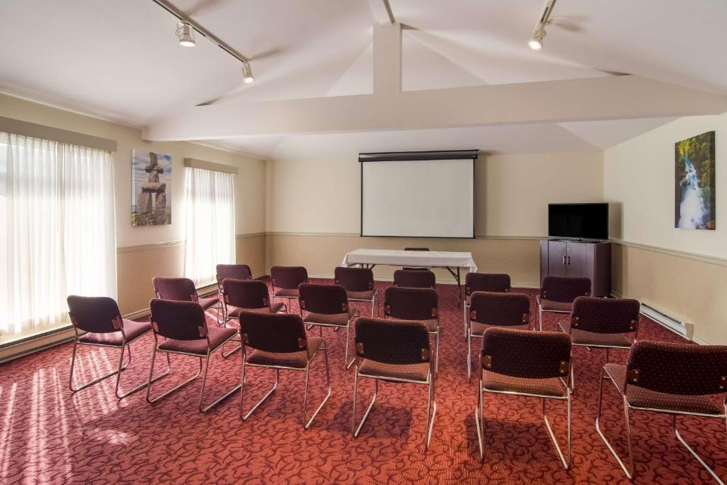 a room with chairs and a white table and a screen at SureStay Hotel by Best Western North Vancouver Capilano in North Vancouver