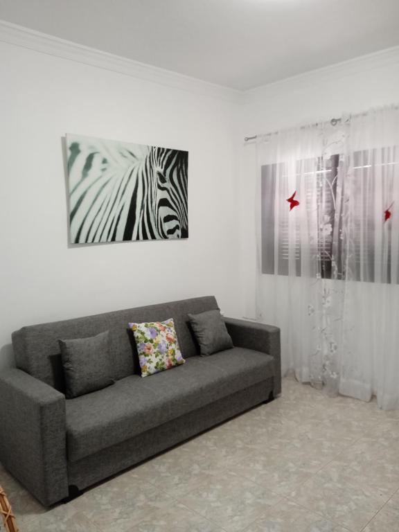 a living room with a couch and a picture of a zebra at adosado cerca del mar in Playa Honda