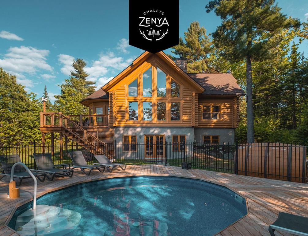 a log cabin with a swimming pool in front of a house at Chalet White Wolf SPA at Fiddler's Lake in Mille-Isles