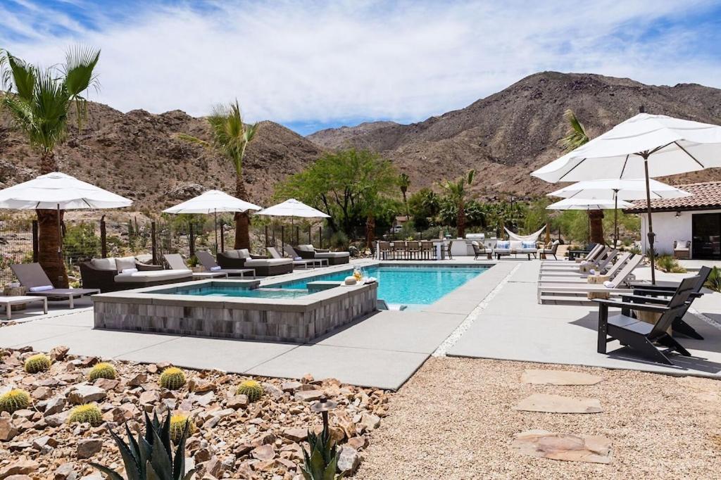 a pool with chairs and umbrellas in a resort at NEW Experience Base Camp An Exclusive Mountainside Desert Resort with 2 Pools in Palm Desert