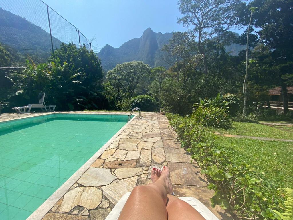 een persoon op een richel naast een zwembad bij Sítio com piscina e churrasqueira in Guapimirim