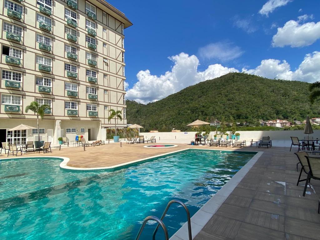 uma piscina num hotel com uma montanha ao fundo em Flat 217 Granja Brasil - Com Piscina Aquecida Em Itaipava em Itaipava