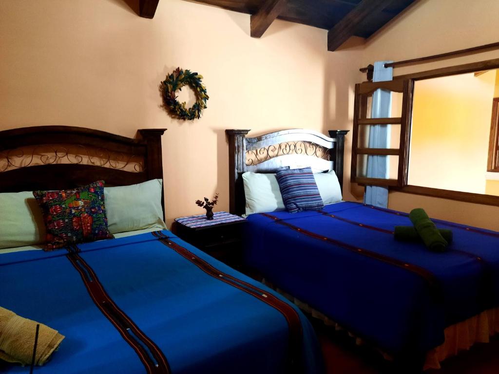 a bedroom with two beds with blue sheets and a mirror at Hotel Casa Sofia in Antigua Guatemala