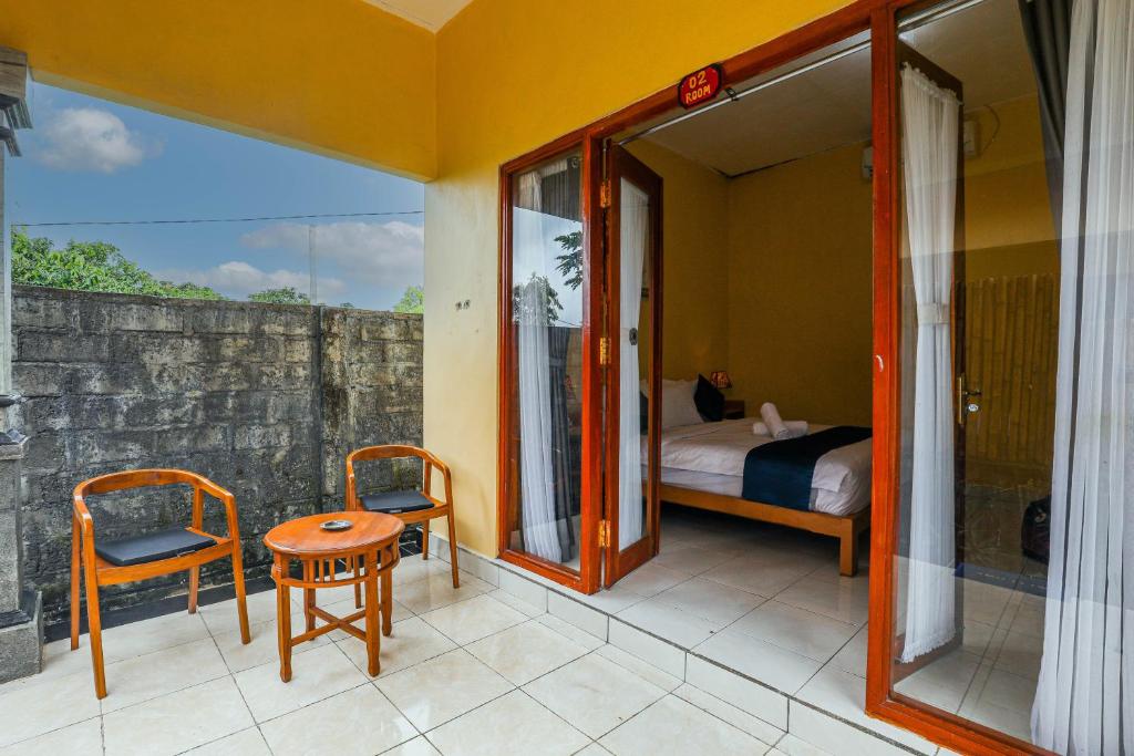 1 dormitorio con cama y balcón con mesa y sillas. en The Salang Guest House, en Nusa Penida
