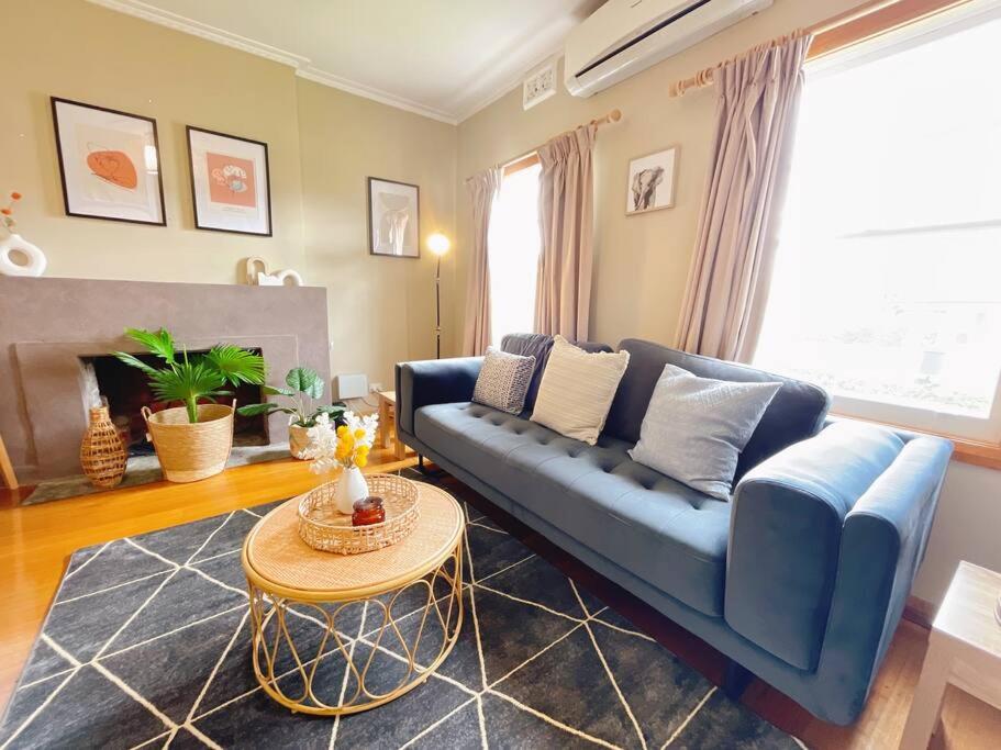 a living room with a blue couch and a table at Stunning Hobart 3-bed home- close to shopping centers in Glenorchy