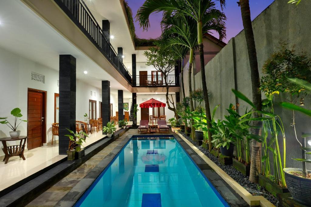a swimming pool in the middle of a house with plants at Graha Wedha Suite Kuta by kamara in Kuta