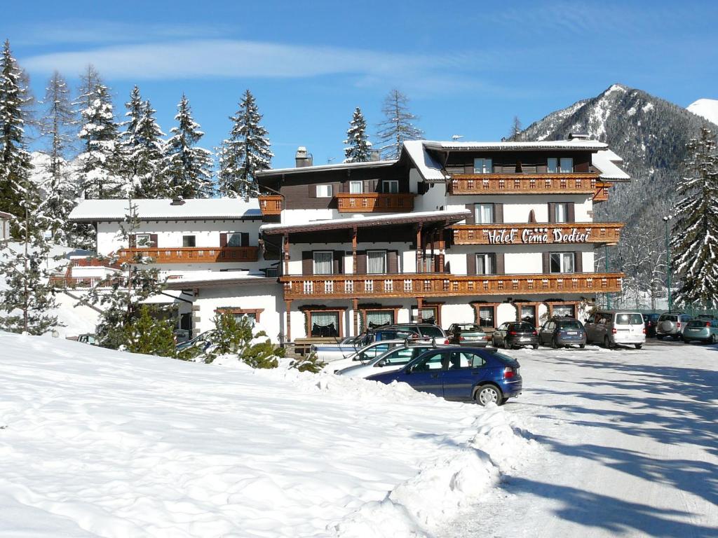 a large building with a car parked in the snow at Hotel Cima Dodici in Vigo di Fassa