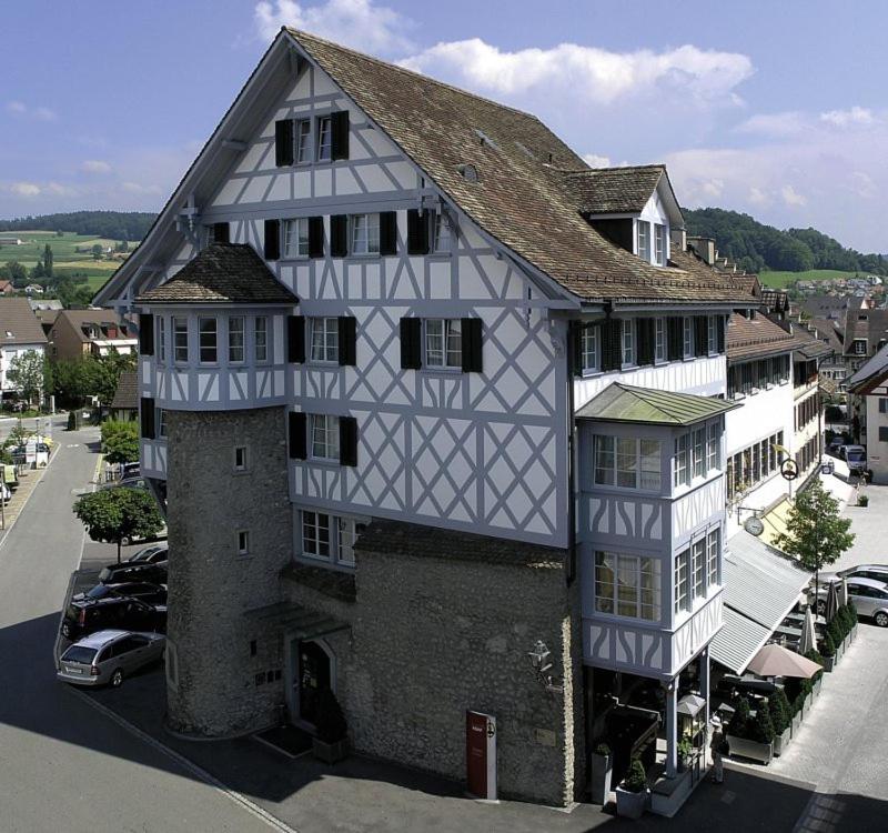 un gran edificio blanco y gris con coches aparcados delante de él en Hotel Restaurant zum goldenen Kopf, en Bülach