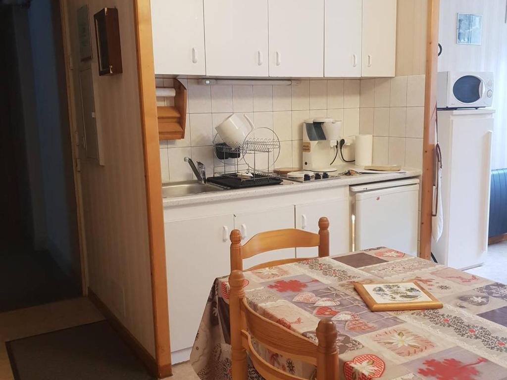 a small kitchen with a table and a sink and a refrigerator at Appartement Cauterets, 2 pièces, 4 personnes - FR-1-234-299 in Cauterets