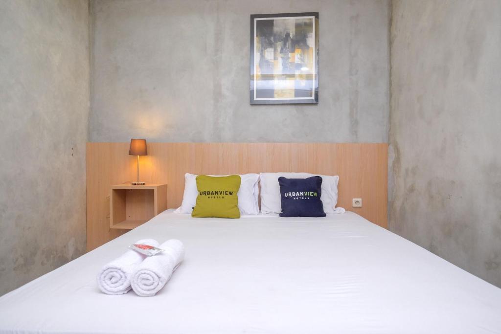 Un dormitorio con una cama blanca con toallas. en Urbanview Hotel Syariah Artamara Tegal by RedDoorz, en Tegal