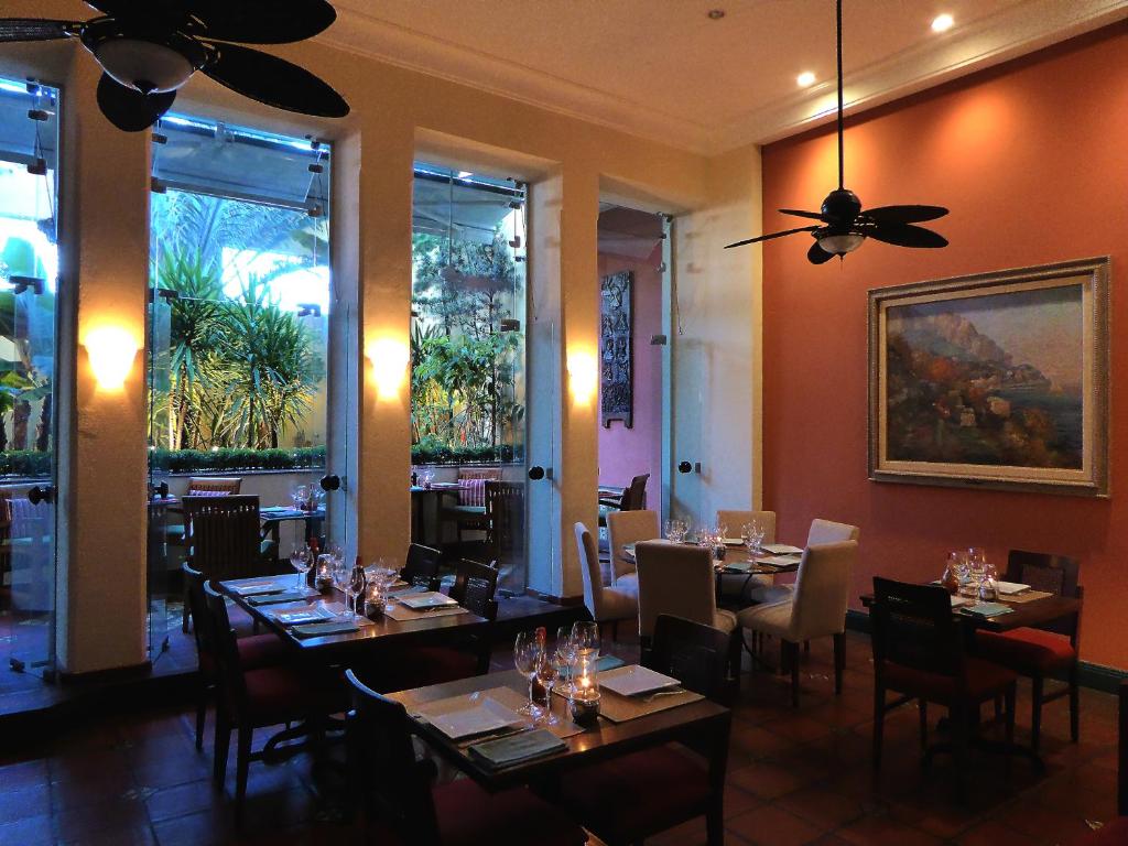 a dining room with tables and chairs and a ceiling fan at Hotel Casa do Amarelindo in Salvador