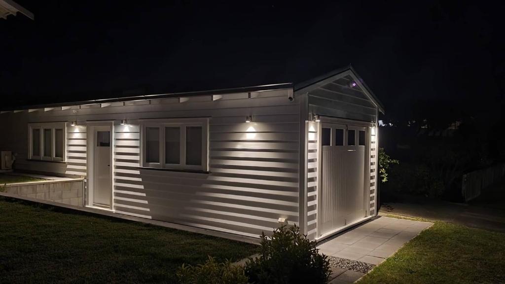 a small white shed with lights on it at night at Retro on Queen, Papakura in Papakura