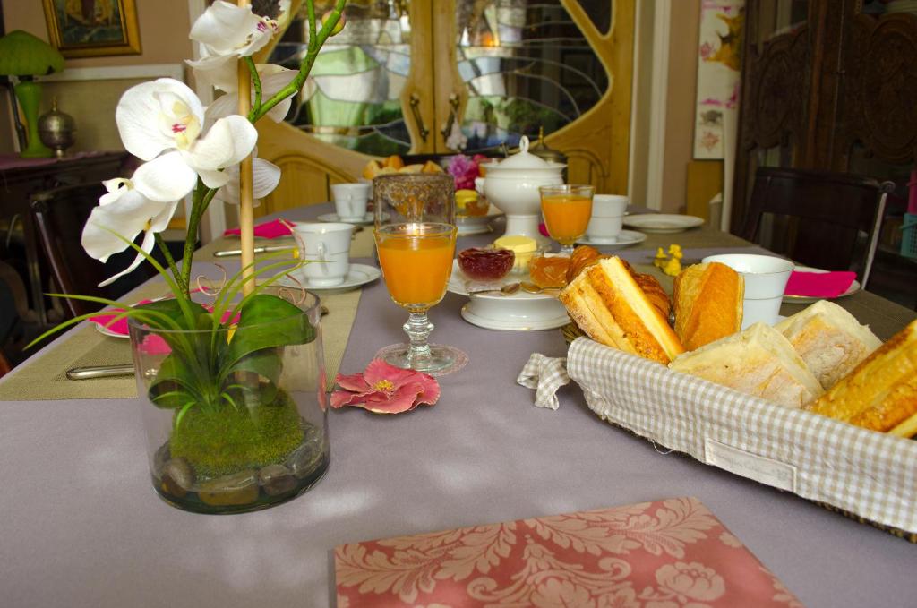 een tafel met brood en sinaasappelsap en bloemen erop bij Chambres d'hôtes Villa l'espérance in Étretat