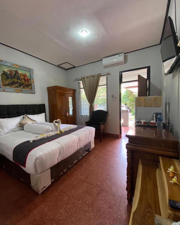 a bedroom with a large bed and a desk and a table at Guest House Pondok Puspa Ayu in Kuta