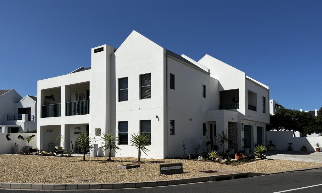 a white building with palm trees in front of it at Clam Lagoon in Langebaan