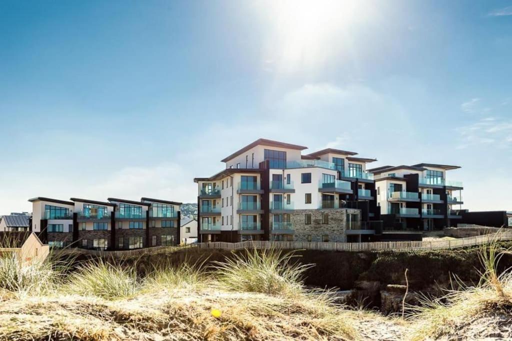un edificio en la cima de una playa junto a la arena en Luxury Sunrise to Sunset Beachfront Apartment, en Perranporth