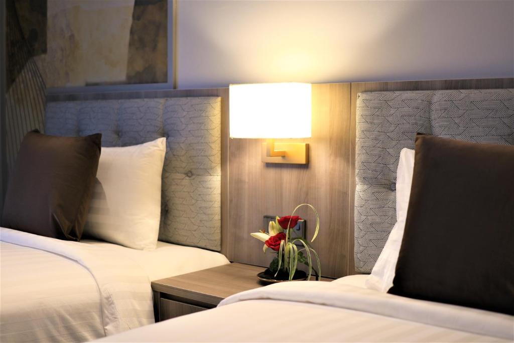 a hotel room with two beds and a table with flowers at KSL ESPLANADE HOTEL with HOT SPRING in Klang
