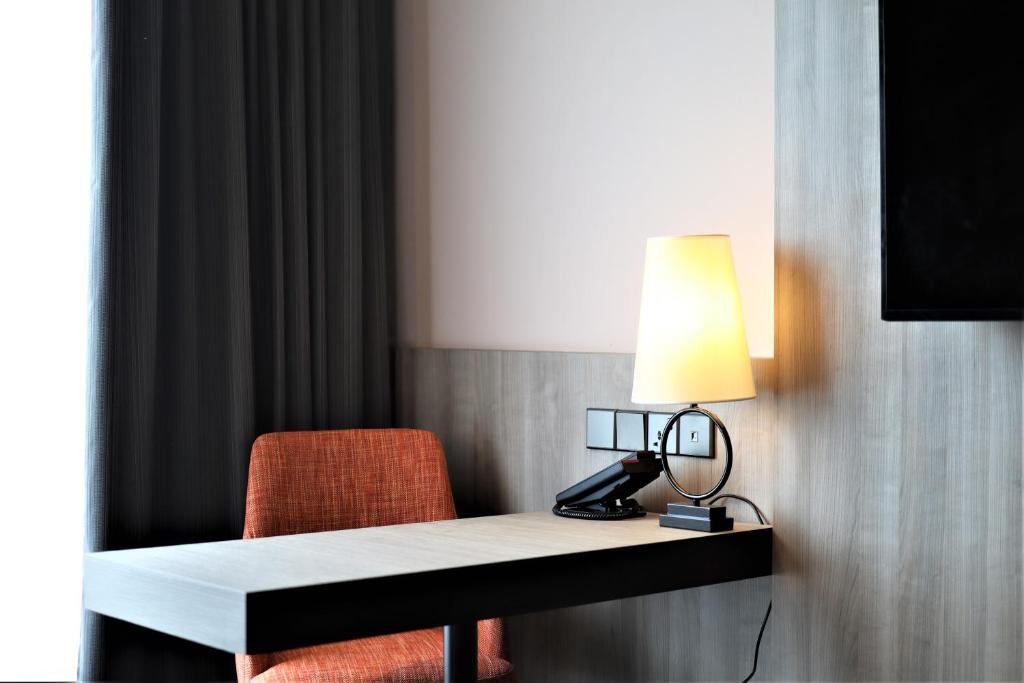 a desk with a lamp and a chair in a room at KSL ESPLANADE HOTEL with HOT SPRING in Klang