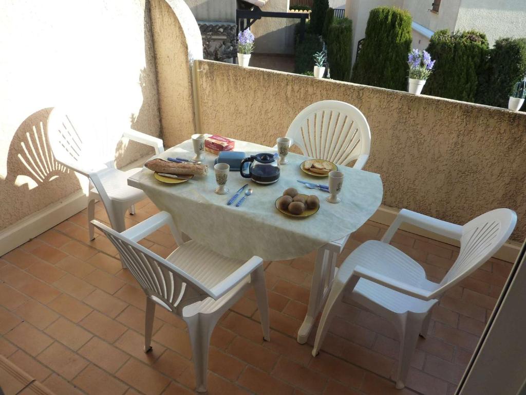 d'une table et de chaises avec de la nourriture sur le balcon. dans l'établissement Agréable Appart 4 Pers. Proche Plage avec Terrasse et Parking Privé - FR-1-387-45, à Marseillan